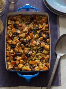 A pan of fig, herb, and sausage stuffing with a serving spoon.