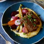 A bowl of white wine braised short ribs with vegetables over white cheddar polenta.