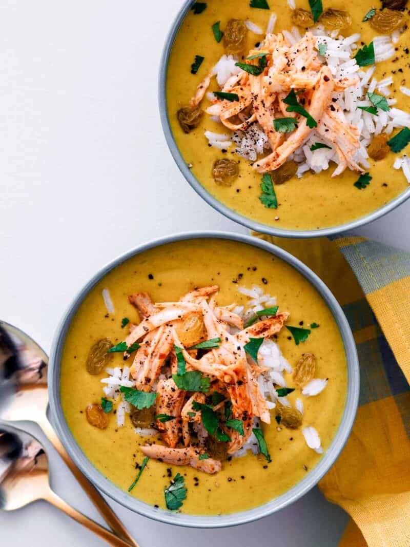 Overhead view of bowls of one pot chicken mulligatawny soup with a spoon.