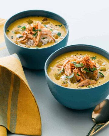 Bowls of one pot chicken mulligatawny soup with a spoon.