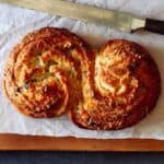 Cheesy roasted garlic and herb pane bianco with a knife.