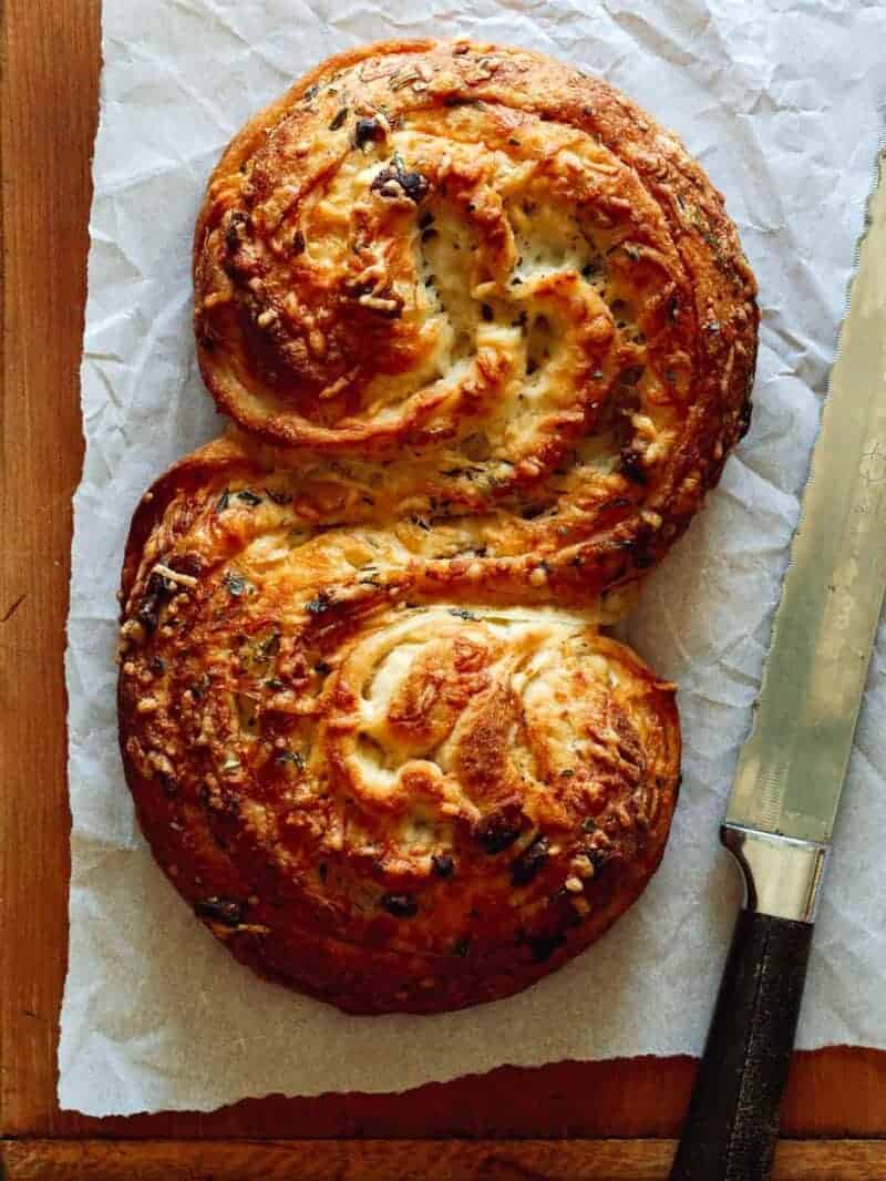 Cheesy roasted garlic and herb pane bianco with a knife.