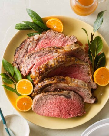 A plate of sliced standing rib roast garnished with orange halves, part of our Christmas Dinner Ideas.