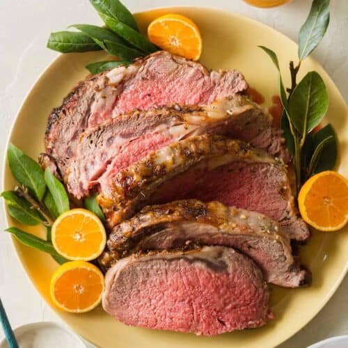 A plate of sliced standing rib roast garnished with orange halves, part of our Christmas Dinner Ideas.