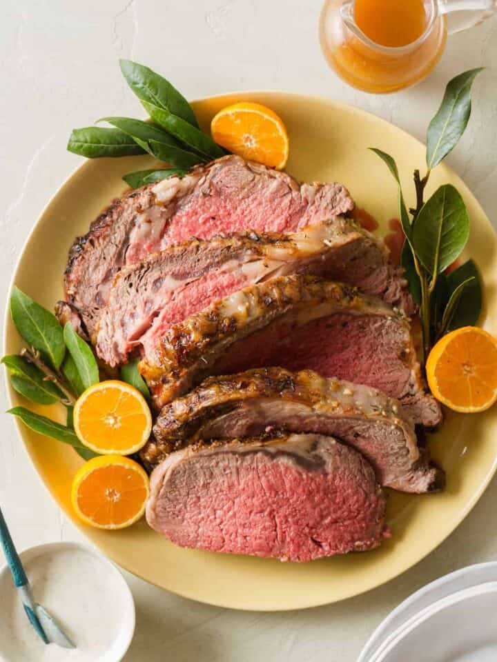 A plate of sliced standing rib roast garnished with orange halves, part of our Christmas Dinner Ideas.