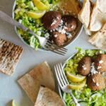Falafel salad hummus bowls with forks and grilled pita bread.