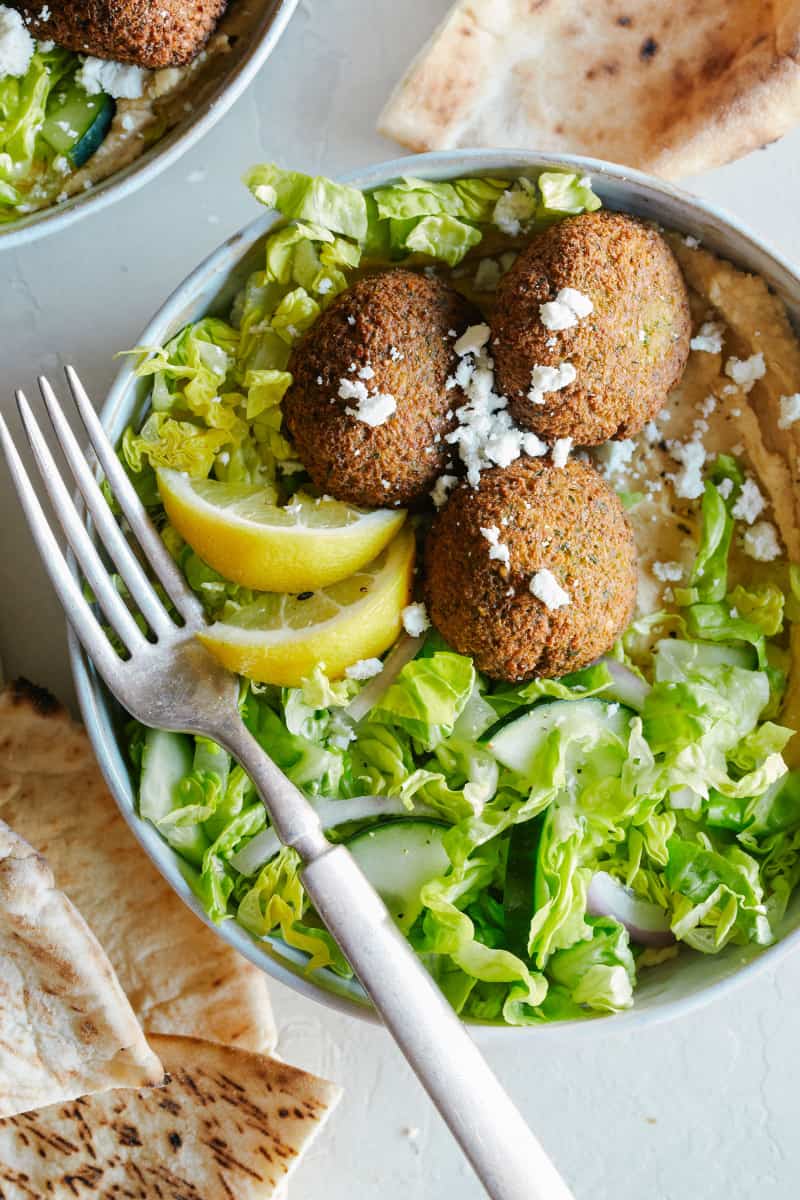 A close up of a falafel salad hummus bowls with a fork.