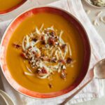 A bowl of roasted sweet potato and leek soup with a spoon.