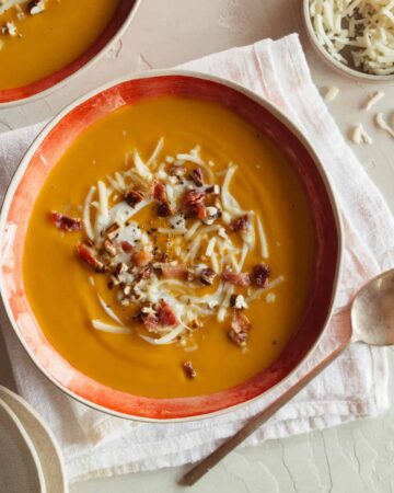 A bowl of roasted sweet potato and leek soup with a spoon.
