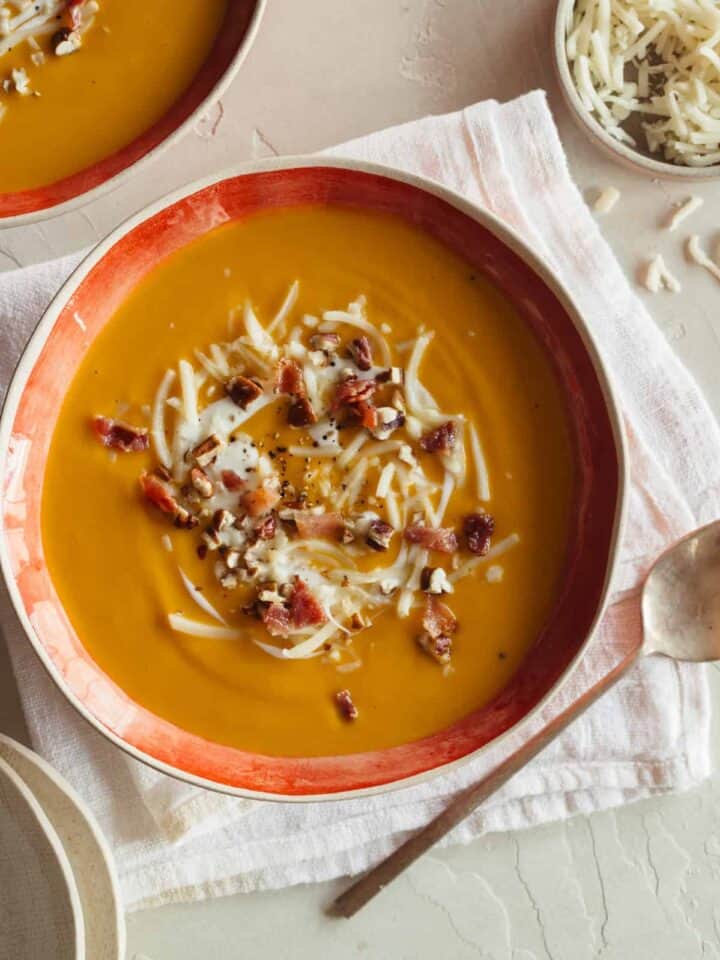 A bowl of roasted sweet potato and leek soup with a spoon.