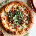 A whole roasted sweet potato, salami, and arugula pizza.