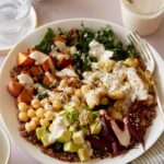 A light and fresh Buddha bowl topped with creamy garlic cashew sauce and a fork.