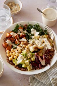 A light and fresh Buddha bowl topped with creamy garlic cashew sauce and a fork.