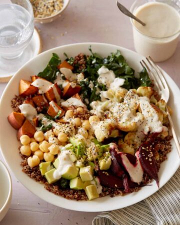 A light and fresh Buddha bowl topped with creamy garlic cashew sauce and a fork.