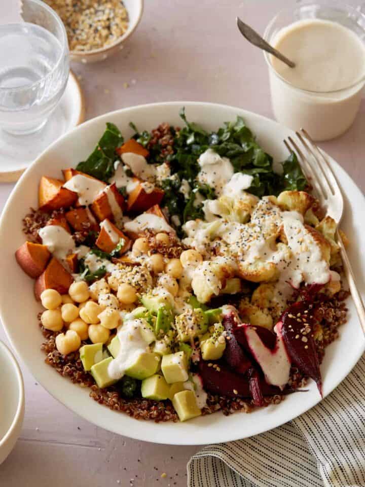 A light and fresh Buddha bowl topped with creamy garlic cashew sauce and a fork.