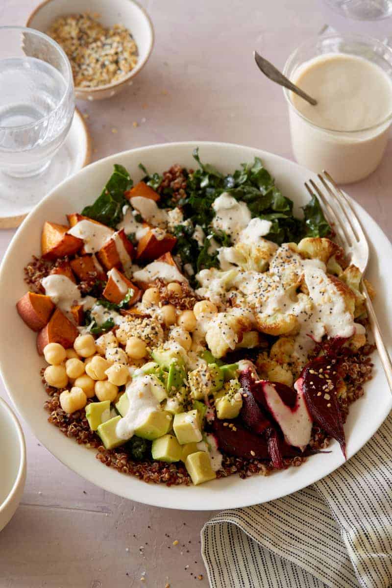 A light and fresh Buddha bowl topped with creamy garlic cashew sauce and a fork.