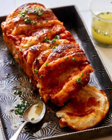 Pizza pull apart bread with a spoon and garlic herb butter.
