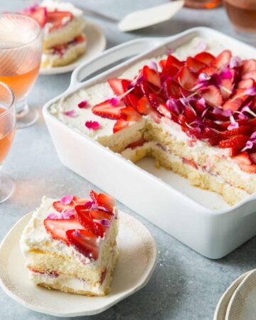 A sliced strawberry tiramisu with a piece on a small plate.
