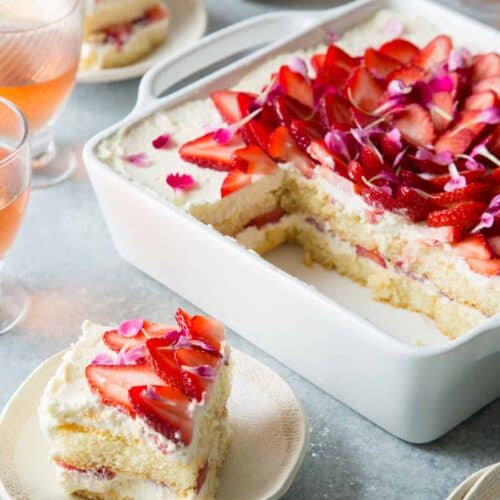 A sliced strawberry tiramisu with a piece on a small plate.