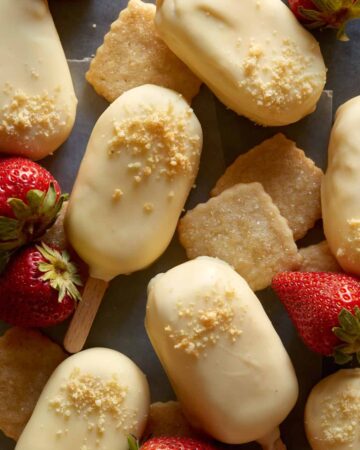 White chocolate dipped no bake strawberry cheesecake bars with fresh strawberries.