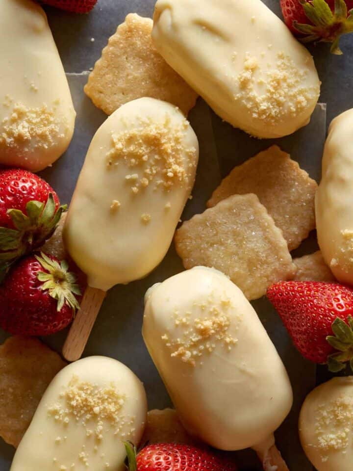 White chocolate dipped no bake strawberry cheesecake bars with fresh strawberries.