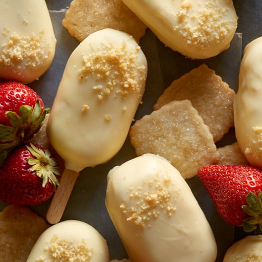 White chocolate dipped strawberry cheesecake bars with strawberries and pound cake.