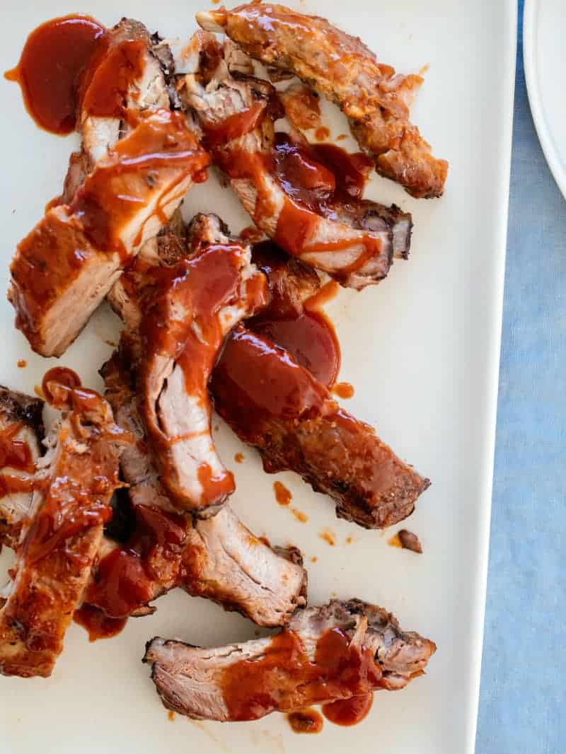 Baby back ribs on a platter smothered with a sweet honey BBQ sauce. 