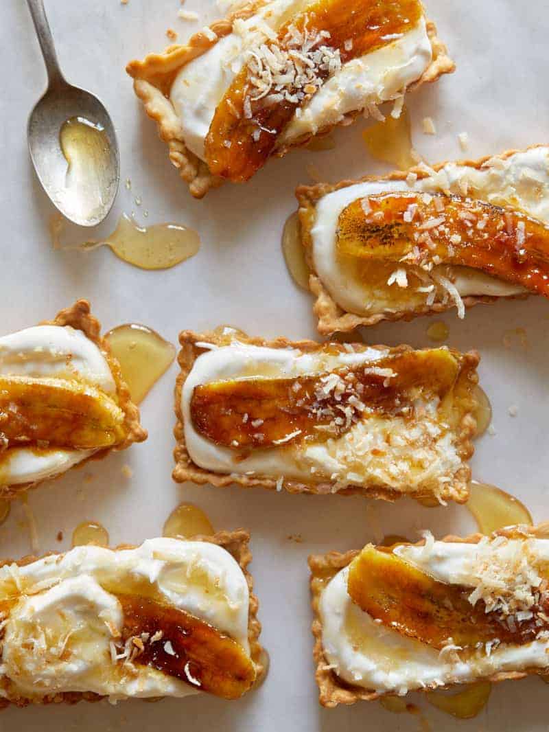 Banana cream tarts drizzled with honey on a piece of parchment. 