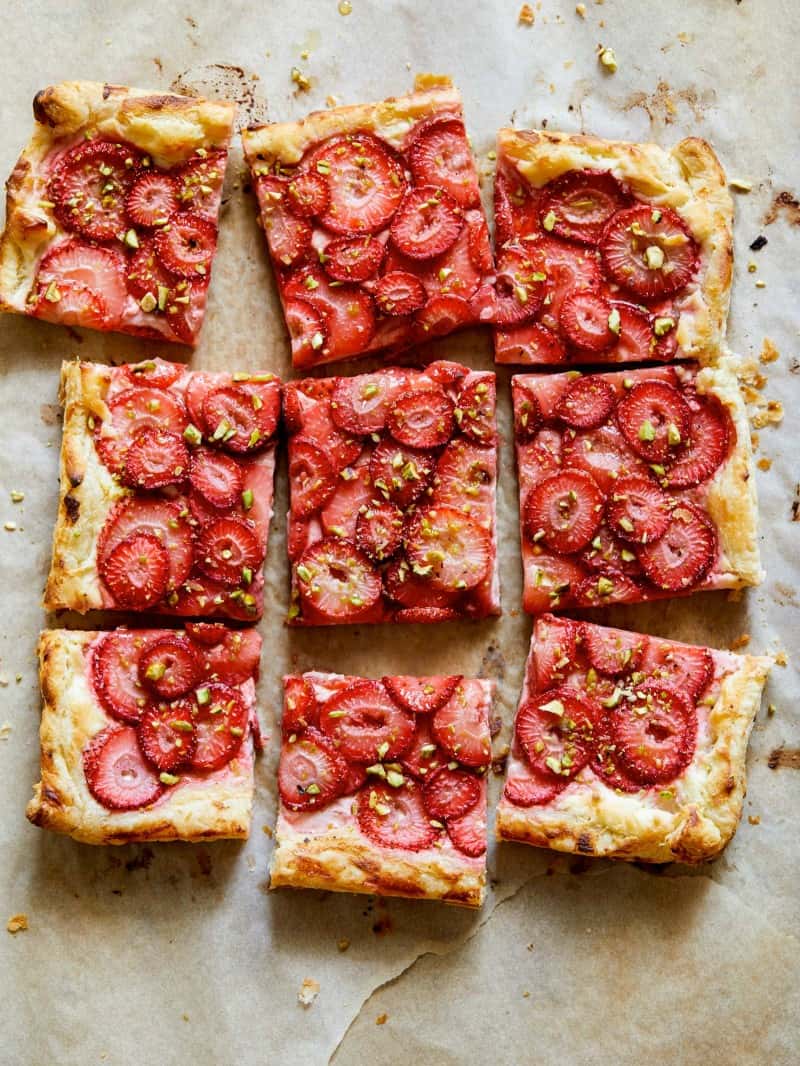 Strawberry Tart cup up ready to be served sitting on a baking sheet with parchment paper. 
