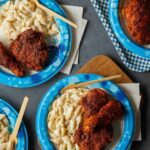 Dixie paper plates of Nashville hot chicken with mac and cheese and disposable wood forks.