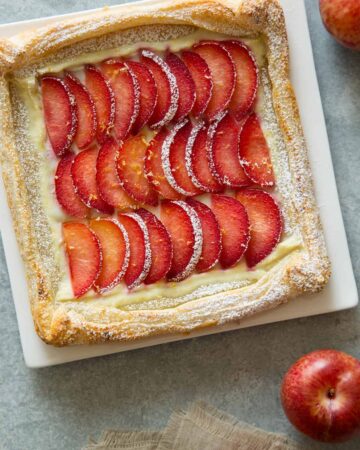 A stone fruit tart on a square plate.