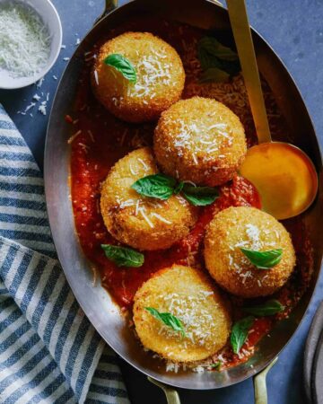 Giant baked cauliflower arancini on a plate with a spoon.