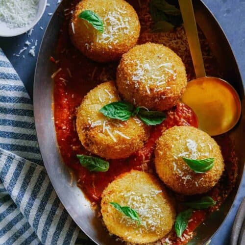 Giant baked cauliflower arancini on a plate with a spoon.