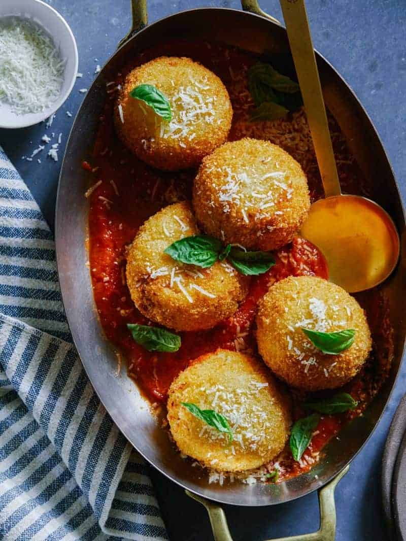 Giant baked cauliflower arancini on a plate with a spoon.