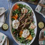 A platter of grilled skirt steak with fresh peaches and burrata.