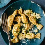 Lobster, corn, and tarragon caramelle on a blue plate with a fork.