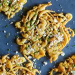 A close up of savory funnel cakes finished with honey, cheese, chives, and sea salt.