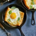 A close up of individual egg and cheese tartlets with forks.