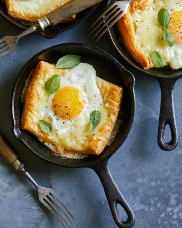 A close up of individual egg and cheese tartlets with forks.