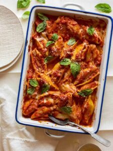 Turkey sausage and mascarpone stuffed shells in a baking dish with a spoon.