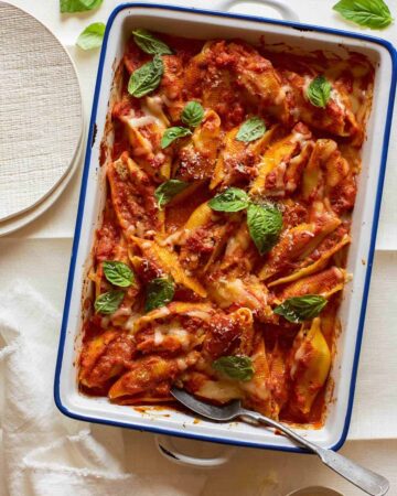 Turkey sausage and mascarpone stuffed shells in a baking dish with a spoon.