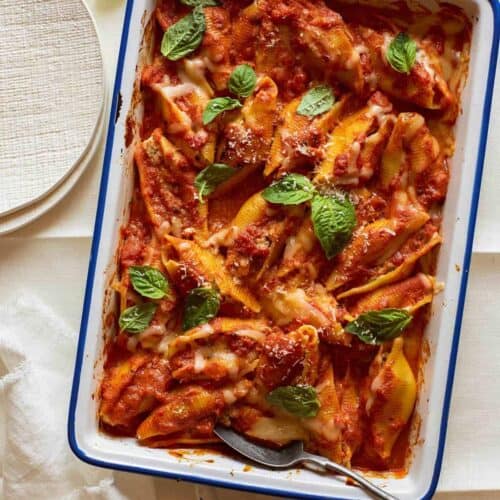 Turkey sausage and mascarpone stuffed shells in a baking dish with a spoon.