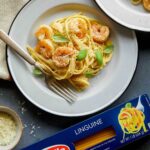 A plate of shrimp linguine with cream sauce next to a box of Barilla linguine.