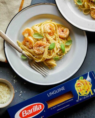 A plate of shrimp linguine with cream sauce next to a box of Barilla linguine.