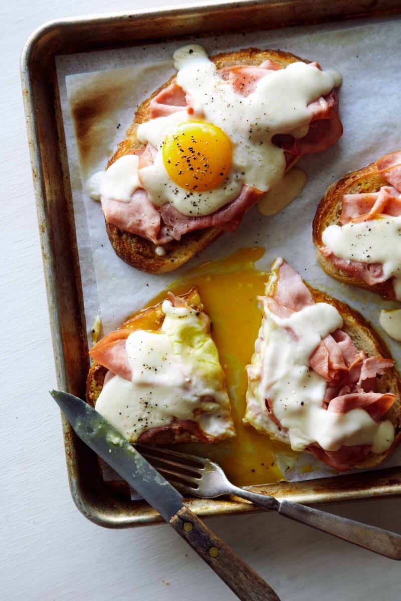 Croque Madame Toast on a baking sheet, cut in half with a knife and fork.