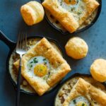 Breakfast pot pies in individual skillets with a fork.