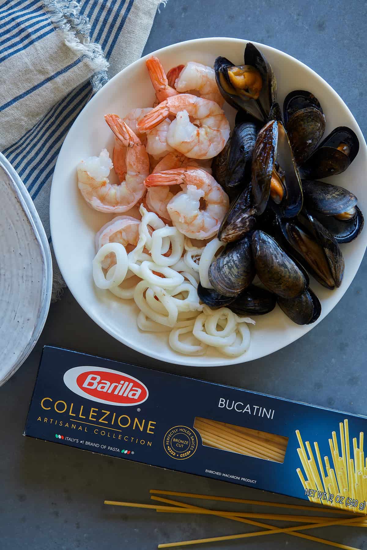 Ingredients for seafood carbonara in a bowl next to a box of Barilla Collezione Bucatini.