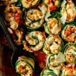 A close up of zucchini lasagna roll ups with a serving spoon.