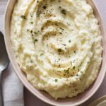 A close up of a bowl of cauliflower parsnip mash with a napkin and spoon.