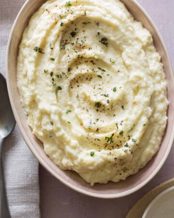 A close up of a bowl of cauliflower parsnip mash with a napkin and spoon.